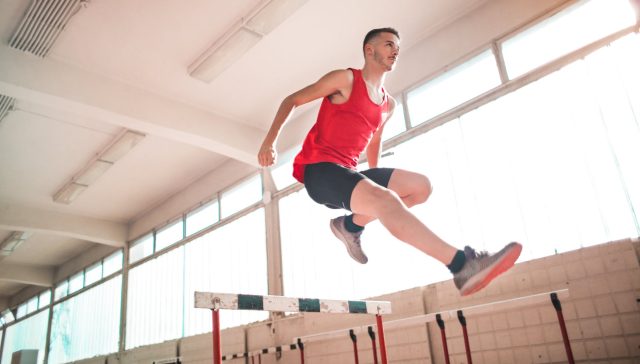 woman in red tank top jumping on obstacle