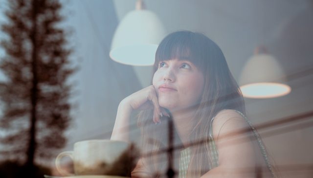 photo of an attractive woman thinking inside a coffee shop