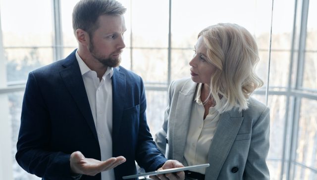 a man holding a tablet while communicating with a woman