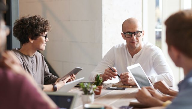 photo of man sitting in front of people