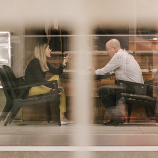 man and woman sitting on black wooden chairs