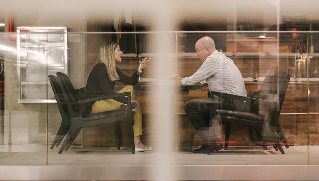 man and woman sitting on black wooden chairs
